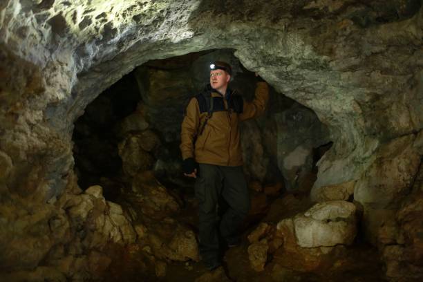 istock Man looks around, standing in a karst cave 1153368448