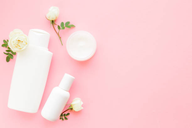 istock Different white toiletries and roses on light pink table. Care about clean and soft face, hands, legs and body skin. Women daily beauty products. Empty place for text or logo. Flat lay. Top view. 1153368558