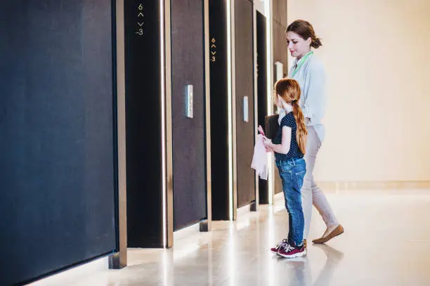 Photo of A side view of businesswoman with small daughter in office building.