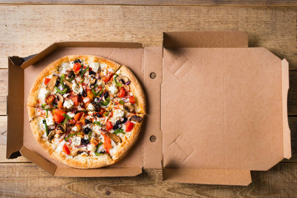 istock Delivery concept. Vegetable pizza in open cardboard box on wooden table 1153370936