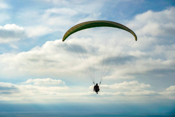 homme faisant du sport (para-planeur). homme parapente dans le ciel obscurci. - action adventure aerospace industry air vehicle photos et images de collection