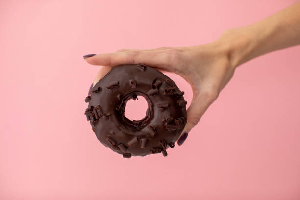 istock Hand with donut on pink background 1153373258