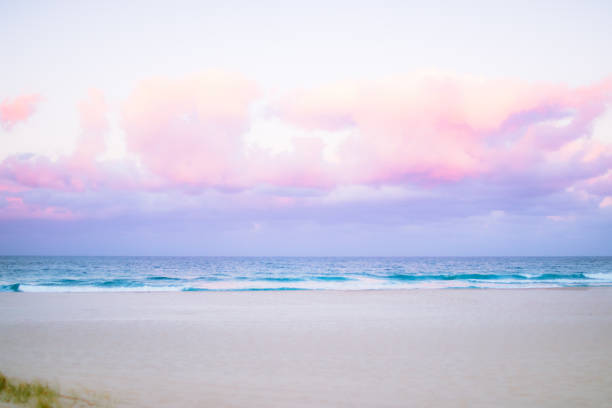 pretty pastel colour sky pink purple blue with fluffy cloud on beach stock photo