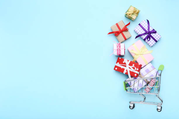 istock Small shopping cart with gift boxes on blue background 1153378059
