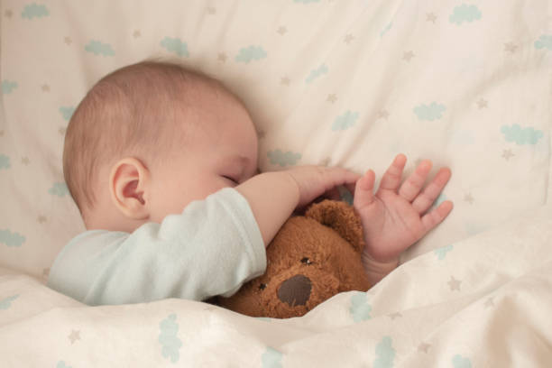 neonato addormentato abbracciando un orso. il bambino addormentato nascondeva il naso in un orsacchiotto. messa a fuoco morbida ravvicinata - baby sleeping bedding teddy bear foto e immagini stock