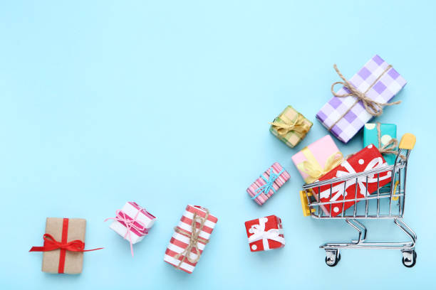 istock Small shopping cart with gift boxes on blue background 1153379111