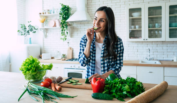 istock Beautiful young woman is preparing vegetable salad in the kitchen. 1153381621