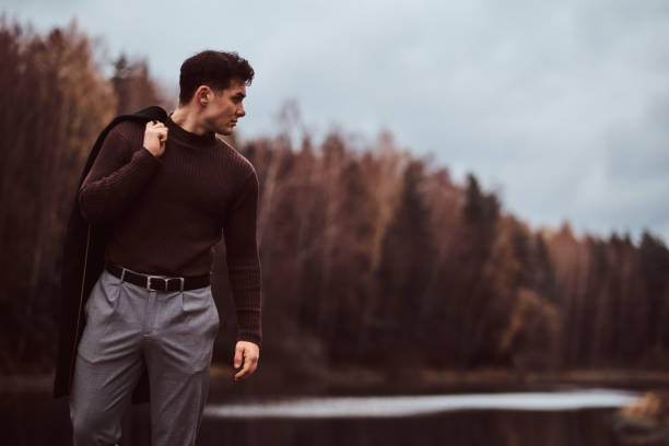 A confident young man near a lake in the autumn forest. stock photo