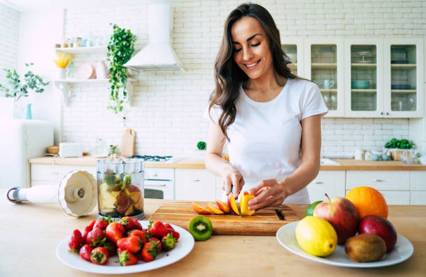 hermosa mujer haciendo batidos de frutas con licuadora. - comida vegana fotos fotografías e imágenes de stock