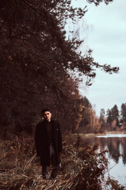 istock A handsome young man standing in the autumn forest. 1153381795