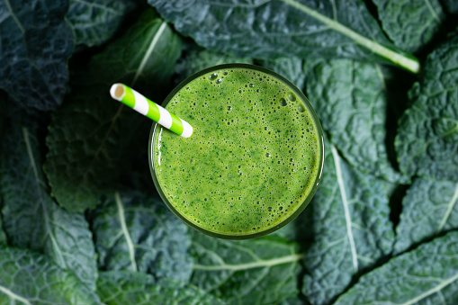 Fresh green smoothie with kale leaves, Healthy green smoothie, on green leaves background