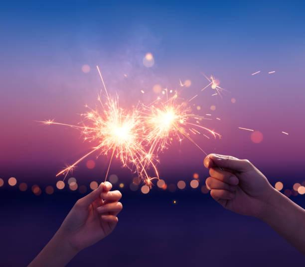 una pareja sosteniendo unas bengalas en la playa - sparkler fotografías e imágenes de stock