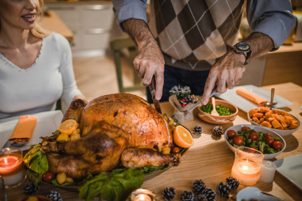 istock Unrecognizable person carving roasted turkey during Thanksgiving dinner at dining table. 1153383768