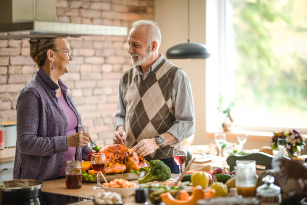 istock Happy senior couple talking while decorating turkey on Thanksgiving day. 1153384003