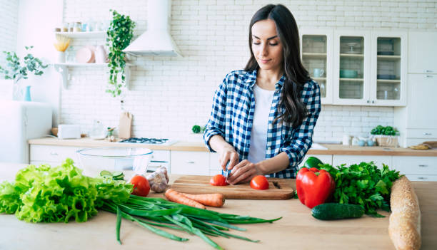 istock Beautiful young woman is preparing vegetable salad in the kitchen. 1153385201