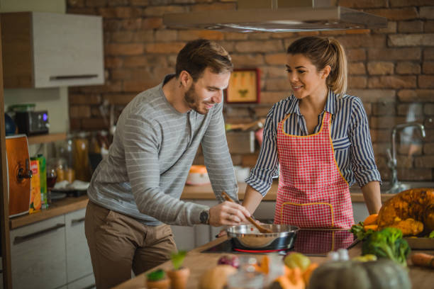 istock Young couple cooperating while cooking side dish for Thanksgiving dinner. 1153385754
