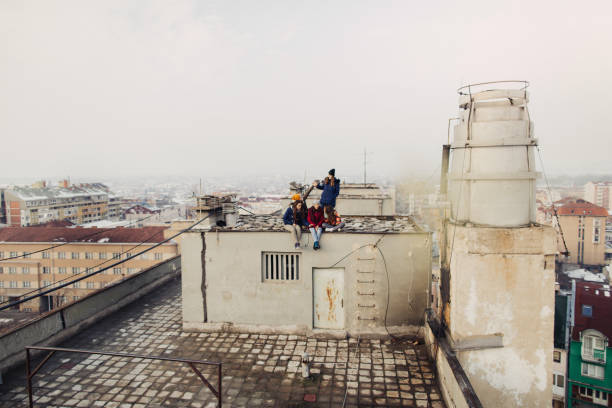 Photo of a group of teenagers hanging out together, on a cold winter day, outdoors on a rooftop
