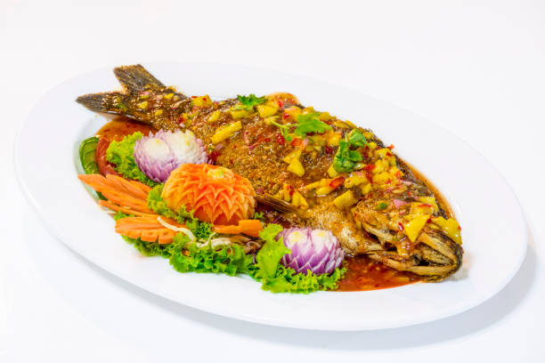 istock Deep Fried Fish with Chilli Sauce fresh herbs on white plate decorate with vegetable carving - Thai Food. 1153391397