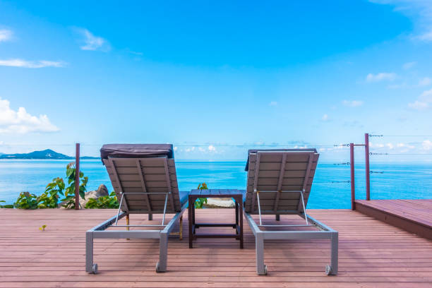 istock Empty Lounge Chairs On Floorboard By Sea Against Blue Sky 1153392117