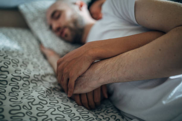istock Gay couple holding hands while sleeping 1153394782