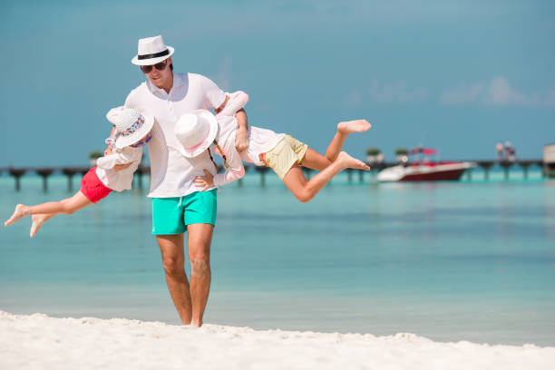 istock Happy father and his adorable little daughters at tropical beach having fun 1153397621