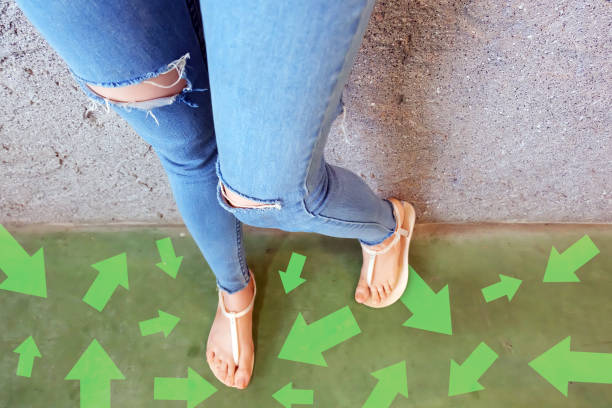 diferentes flechas de dirección hacia el futuro. selfie sobre mujer de pie con opciones de línea de flecha verde. zapatos mujer (calzado) y flechas en street road en el fondo de la ciudad. - choice teenager footpath arrow sign fotografías e imágenes de stock