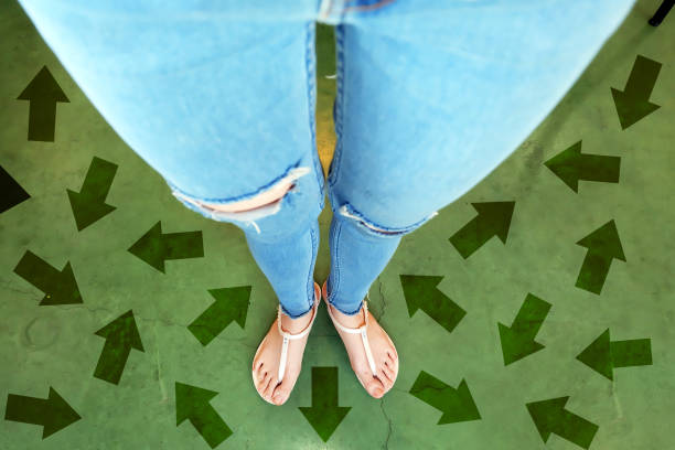 diferentes flechas de dirección hacia el futuro. selfie sobre mujer de pie con opciones de línea de flecha verde. zapatos mujer (calzado) y flechas en street road en el fondo de la ciudad. - choice teenager footpath arrow sign fotografías e imágenes de stock