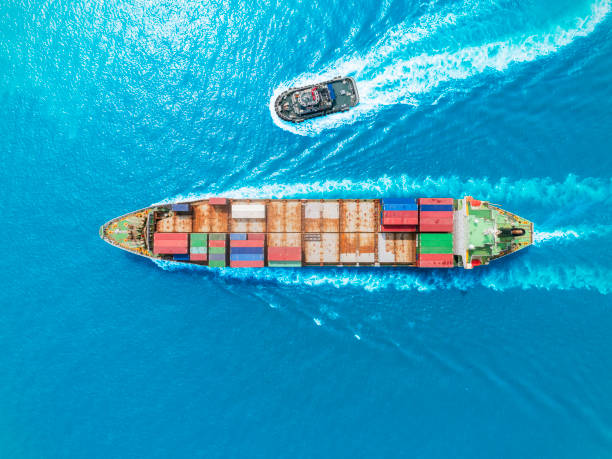 istock Aerial top view container ship and Tugboat going to quayside  for logistics, import export, shipping or transportation. 1153400342