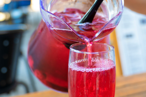 Red sangria poured from a jug into a glass
