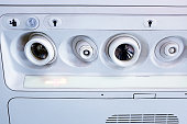 Overhead air vents, lights and oxygen-mask panel in an airplane