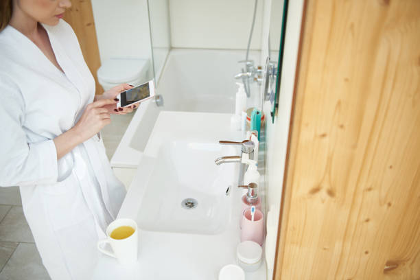 istock Woman in bathrobe standing in the bathroom and using smartphone 1153407827