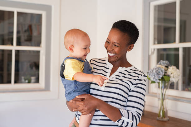 African mother holding adopted child Portrait of happy black mother holding cute toddler laughing together at home. Cheerful african woman cuddling smiling little boy in hand and playing. Mature black nanny playing with little boy. adoption stock pictures, royalty-free photos & images