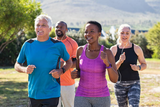 Mature and senior people jogging at park Healthy group of mature people jogging on track at park. Happy senior couple running at park with african friends. Multiethnic middle aged friends exercising together outdoor. vibrant group stock pictures, royalty-free photos & images
