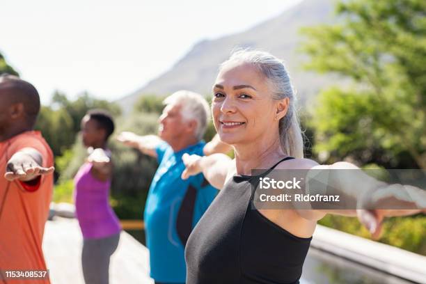 Senior Woman Stretching Arms In Yoga Class Stock Photo - Download Image Now - Exercising, Yoga, Mature Women