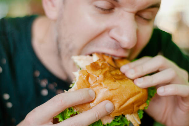 istock Man in a restaurant eating a hamburger, he is hungry and having a good bite. selective focus 1153409446