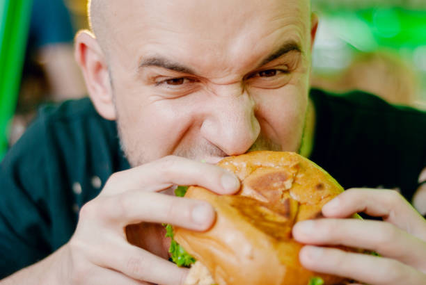 istock Man in a restaurant eating a hamburger, he is hungry and having a good bite. selective focus 1153409456