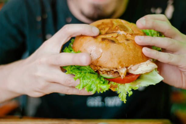 istock Man in a restaurant eating a hamburger, he is hungry and having a good bite. selective focus 1153409564