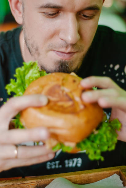 istock Man in a restaurant eating a hamburger, he is hungry and having a good bite. selective focus 1153409592