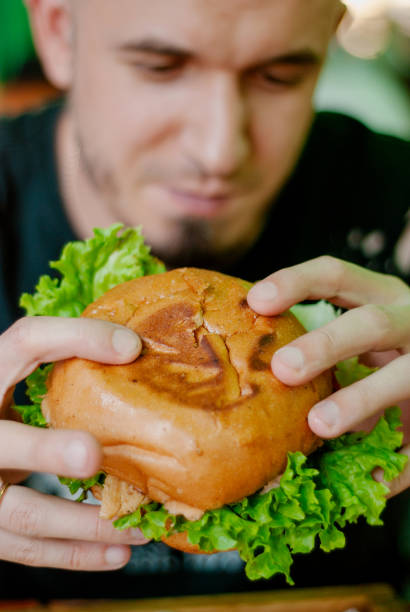 istock Man in a restaurant eating a hamburger, he is hungry and having a good bite. selective focus 1153409620