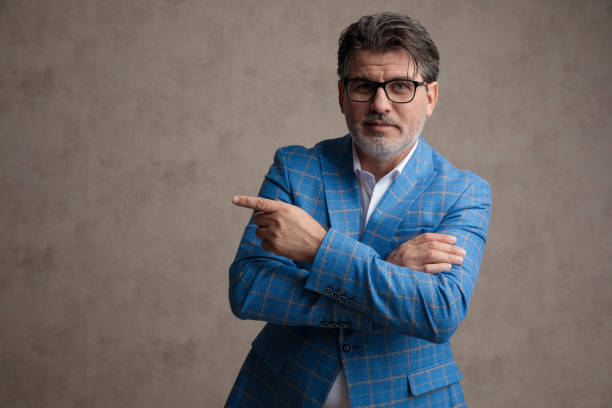 istock Smart businessman pointing to the side with his arms folded 1153409743