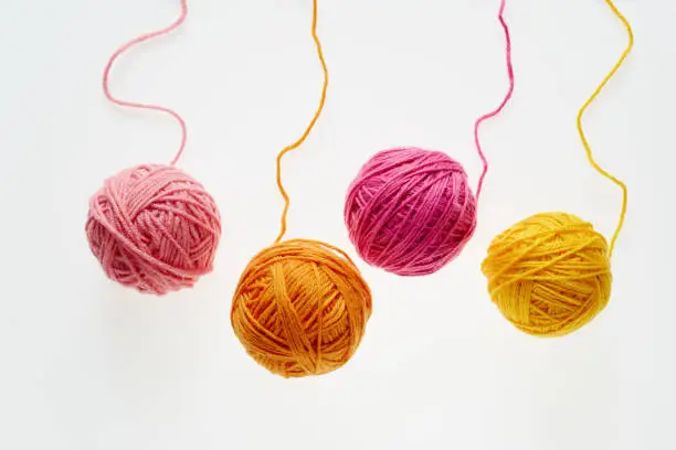 Colorful woolen balls over white background. Balls of wool partially unrolled.