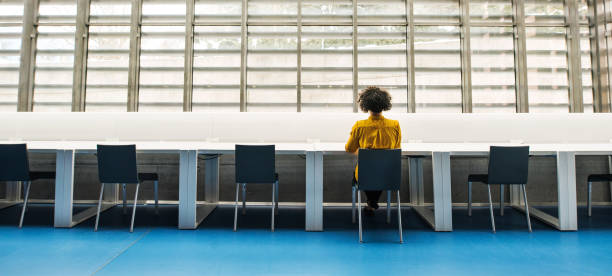 widok z tyłu młodego studenta lub bizneswoman siedzącego na biurku w pokoju w bibliotece. - office furniture open plan desk zdjęcia i obrazy z banku zdjęć