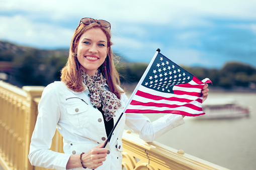 Young urban woman holding USA flag outdoors, 4th of July, Independence day