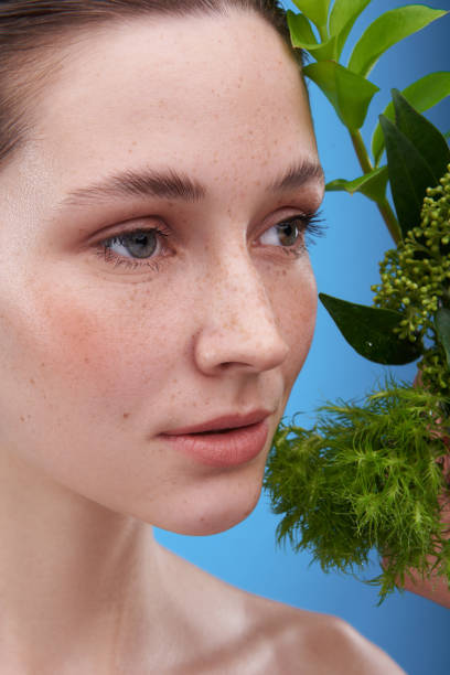 istock Young tender freckled lady with green branch 1153413367