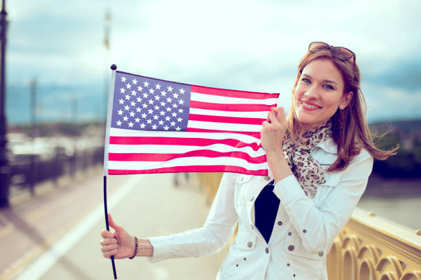 istock Young modern woman holding USA flag 1153413676