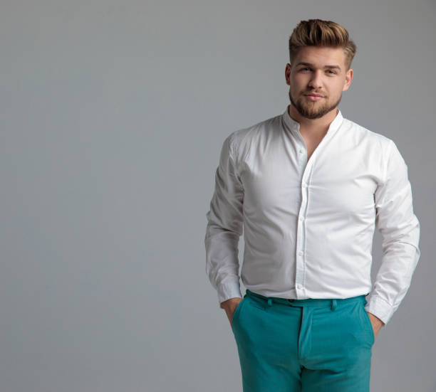 Charming man standing and holding both hands in his pockets