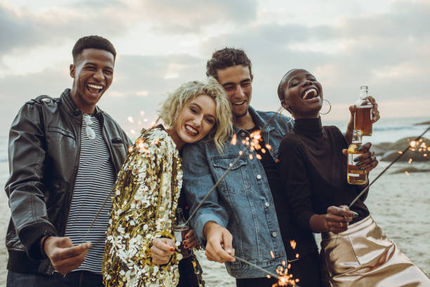 istock Group of friends celebrating with fireworks at beach 1153415796