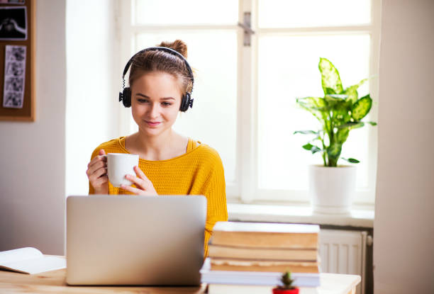 istock A young female student sitting at the table, using headphones when studying. 1153416567