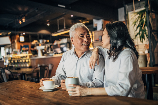Woman and man, senior Taiwanese couple sitting in cafe together.