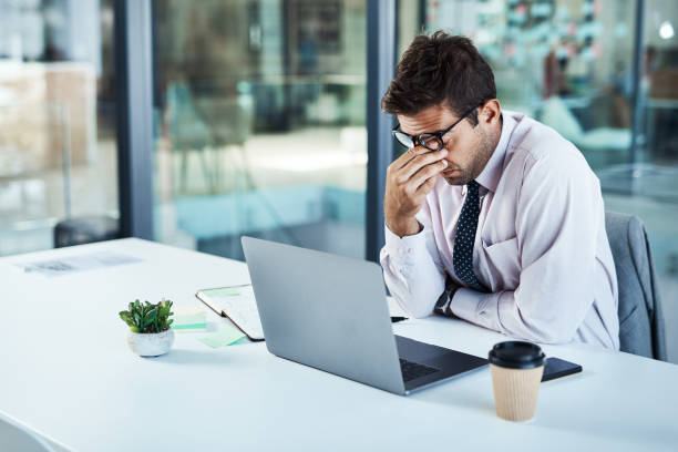 I need a break... Shot of a businessman looking stressed while sitting at his desk business failure stock pictures, royalty-free photos & images